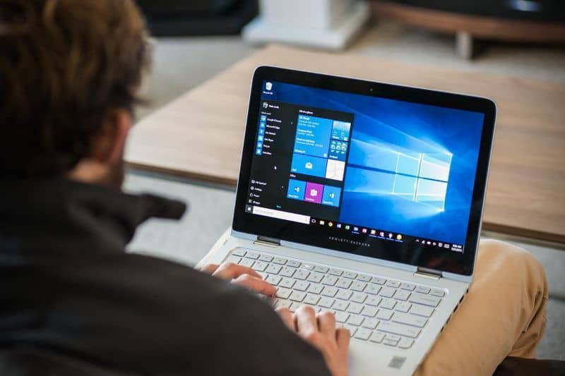 mies ajaa kannettavaa tietokonetta Windows 10: ssä kannettavan tietokoneen jaloilla